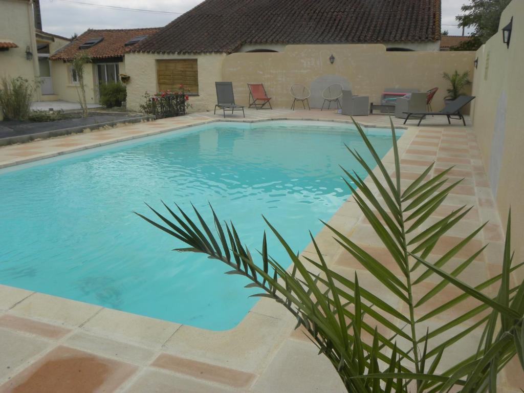 a swimming pool with a palm tree in front of a house at les figuiers et les rosiers proche puy du fou in Saint-Germain-de-Prinçay