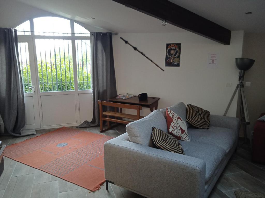 a living room with a couch and a window at les figuiers et les rosiers proche puy du fou in Saint-Germain-de-Prinçay