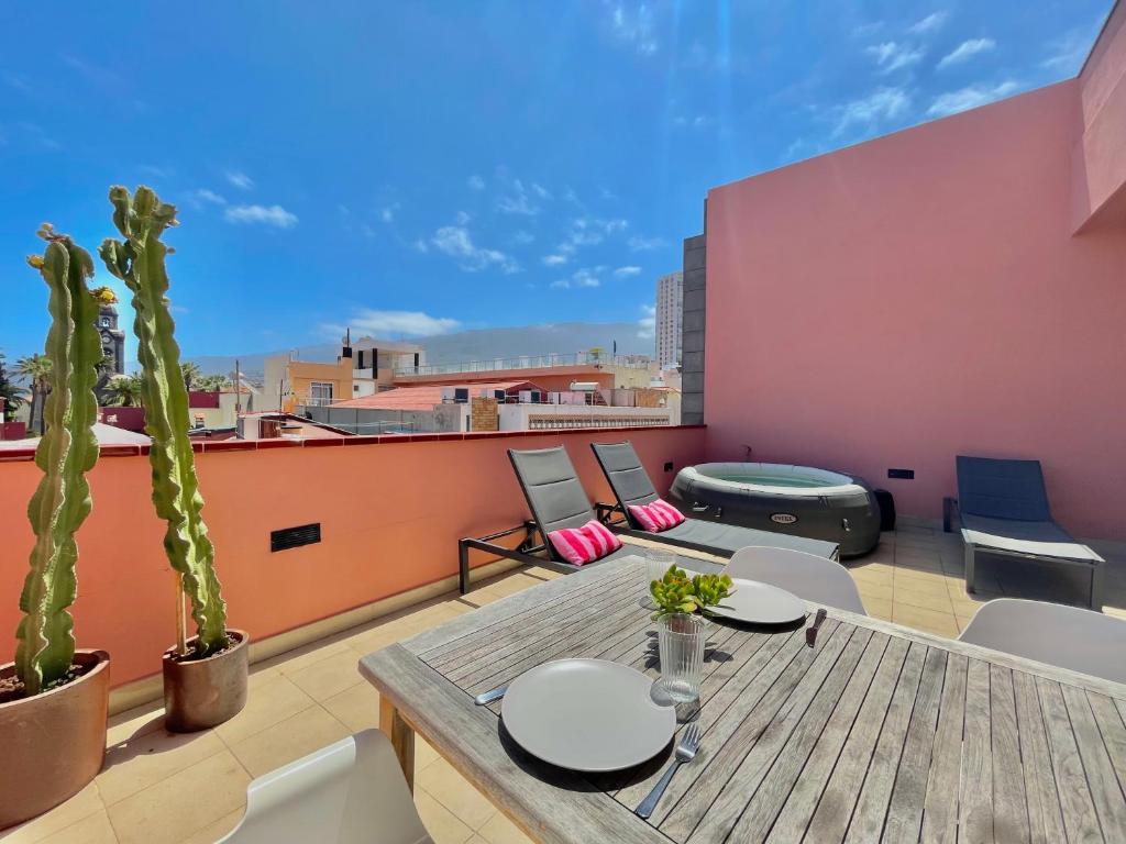 Un patio en la azotea con una mesa y sillas y un cactus. en AROMAS Suites Attic, en Puerto de la Cruz