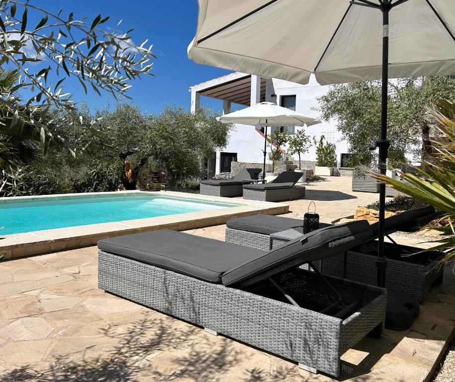 a pool with two lounge chairs and an umbrella at Casa de Olivos - Unique Apartments - Adult Only in Traiguera