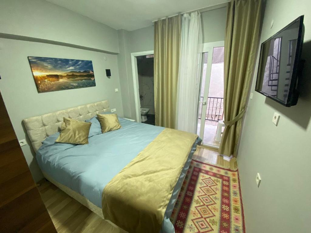 a bedroom with a bed with a television and a balcony at GÜLERSU PANSIYON in Kuşadası
