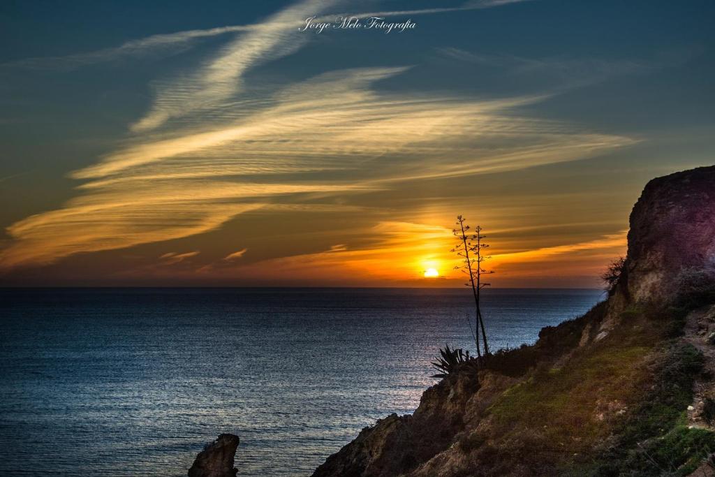 una puesta de sol sobre el océano en un acantilado en Sunny House, en Lagos