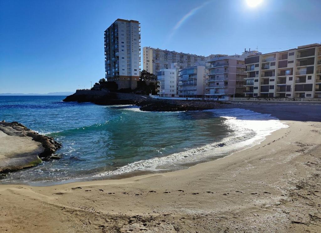 Faro de Cullera II في فارو دي كوييرا: شاطئ فيه بعض المباني والمحيط