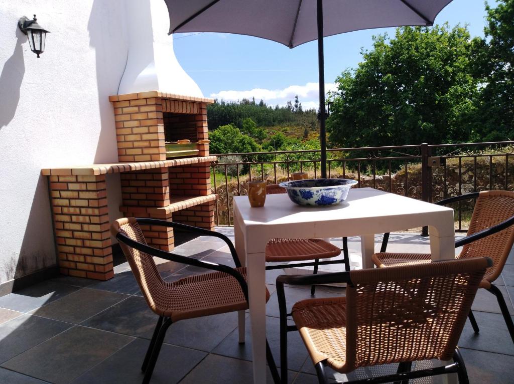 a table and chairs with an umbrella on a patio at Casa Elizabeth in Pedrógão Grande