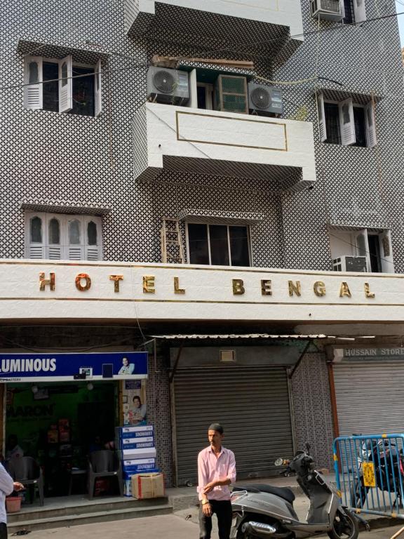 加爾各答的住宿－Hotel Bengal，站在一座建筑物前面的摩托车旁的人