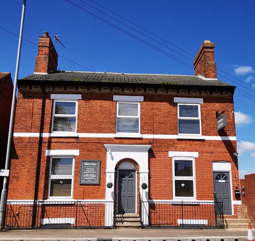 an old red brick building with a black door at Valletta House Holiday Apartments in Skegness