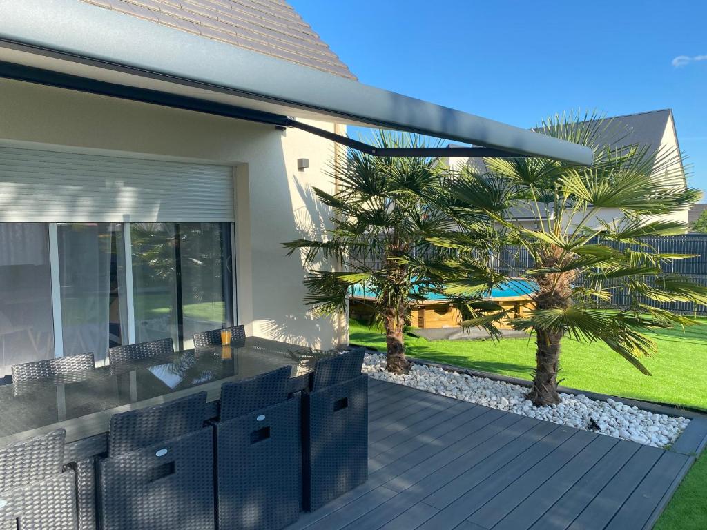 una casa con una terraza con palmeras. en Loue maison pour les 24h du Mans, en Mulsanne