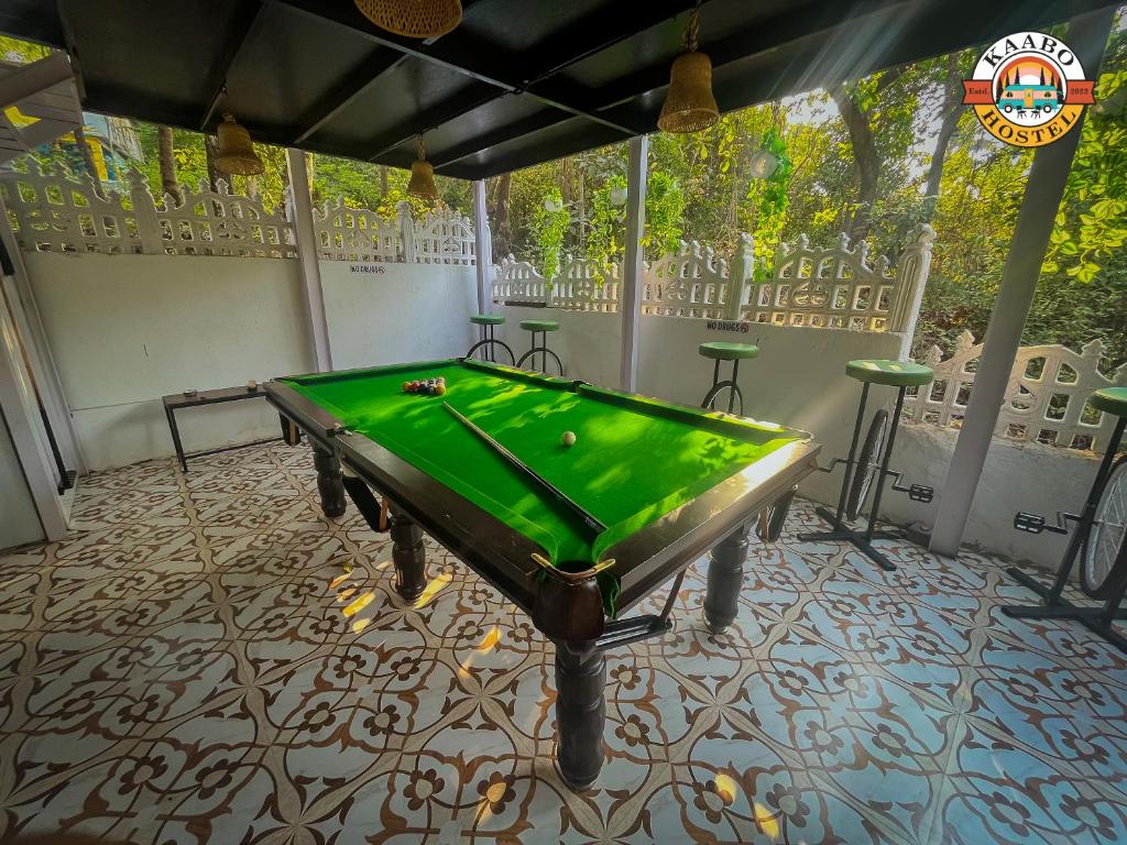 a pool table in a room with a green cloth at Kaabo Hostel in Vagator