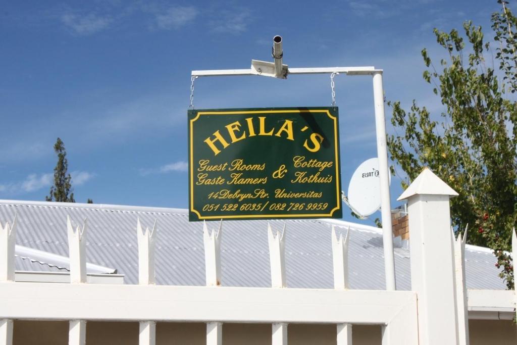 a sign for a hotel on top of a white fence at Heila & Glen's Cottage in Bloemfontein