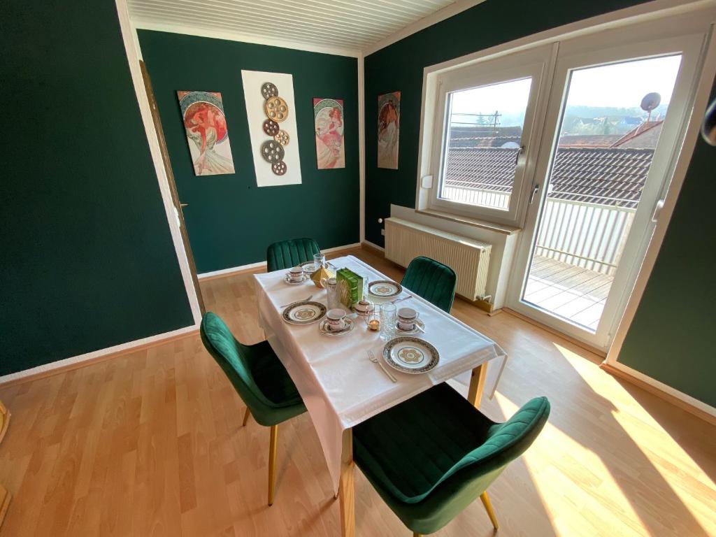 a dining room with a white table and green chairs at Ruhige Ferienwohnung bei Bamberg in Stegaurach
