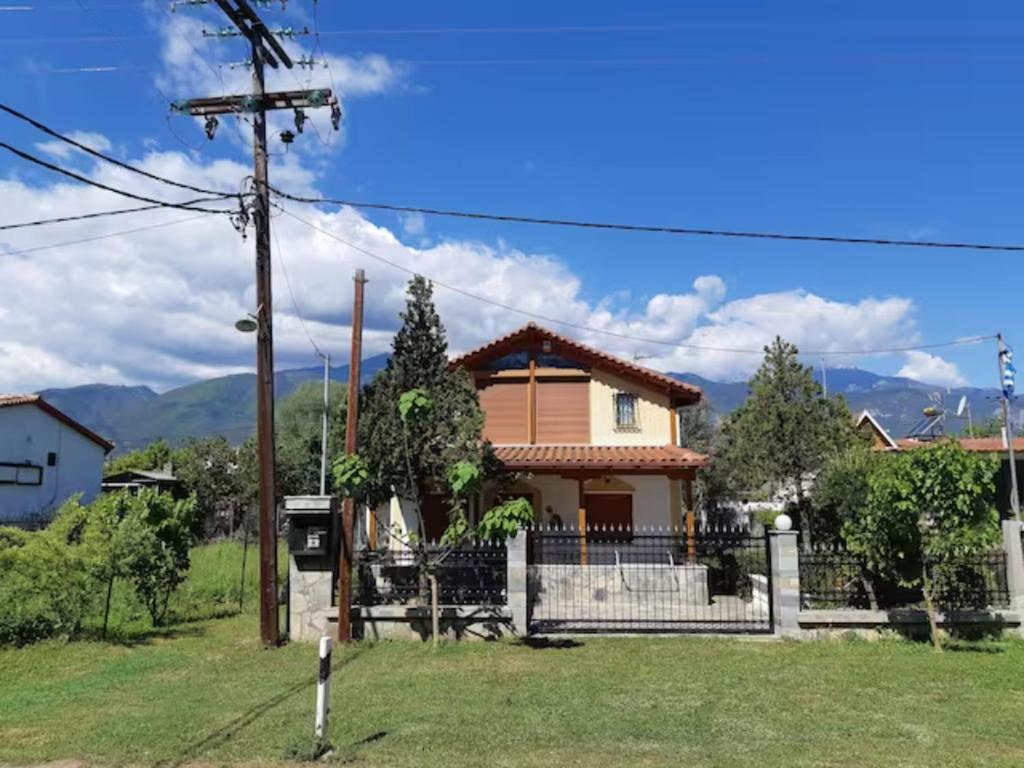 a house with a fence and mountains in the background at Attic close to sea(150m) in Leptokarya -Σοφίτα in Leptokaria