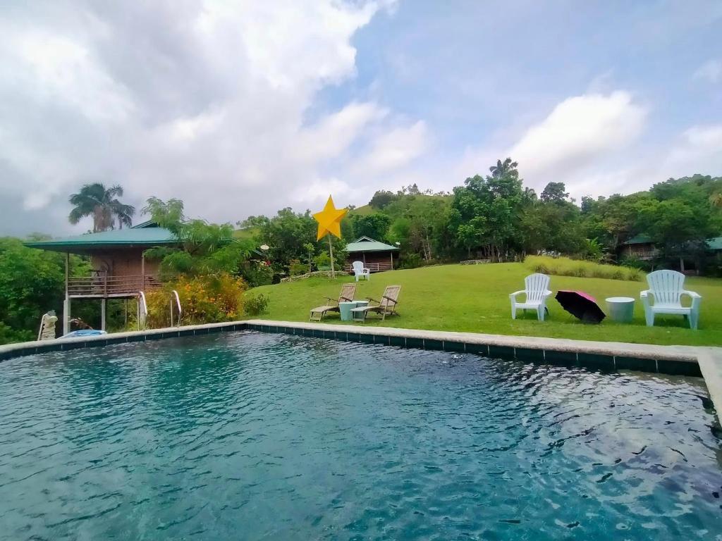 a swimming pool in a yard with chairs and a house at Marquis garden Eco-cottages in Tocdoc