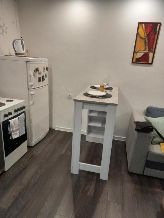 Il comprend une cuisine équipée d'une table blanche et d'un réfrigérateur blanc. dans l'établissement Apartman Mici, à Niš