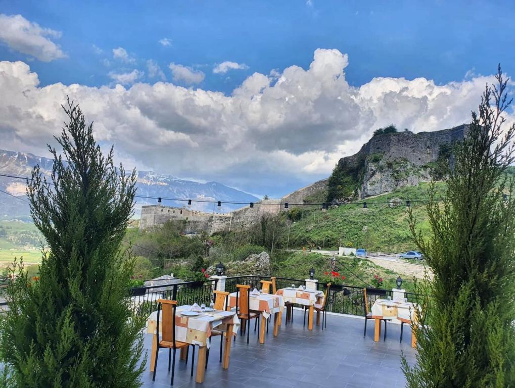 a patio with tables and chairs and a view of the mountains at Castle Hotel in Gjirokastër