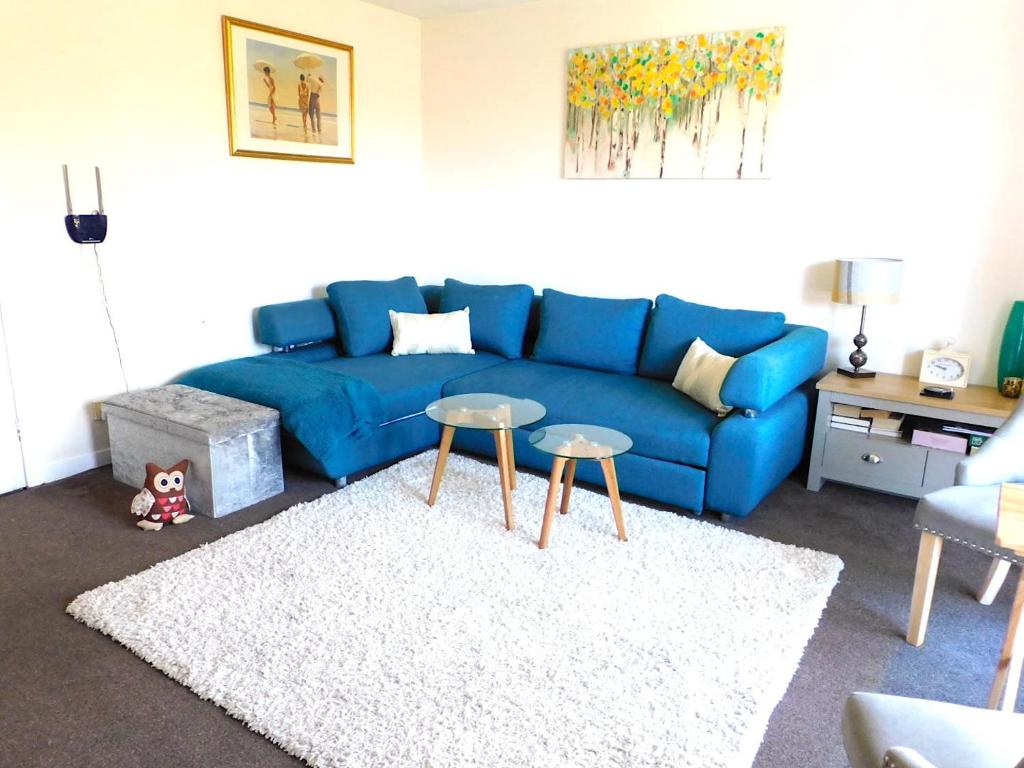 a living room with a blue couch and two tables at Fab Location 1 bed Apt overlooking Glasgow Green in Glasgow