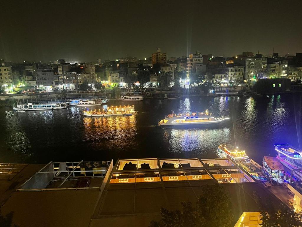 開羅的住宿－Zamalek Two-Bedroom Apartement Nile View，享有夜间河流美景,设有船只
