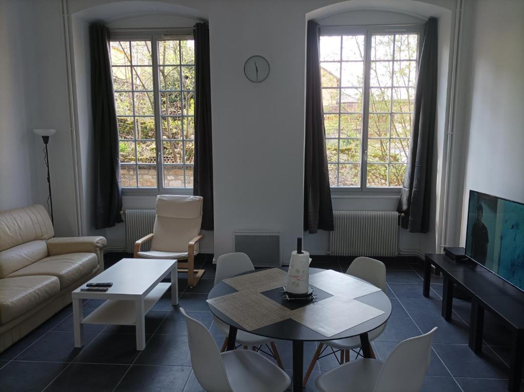 een woonkamer met een bank en een tafel en stoelen bij O'Couvent - Appartement 87m2 - 4 chambres - A511 in Salins-les-Bains