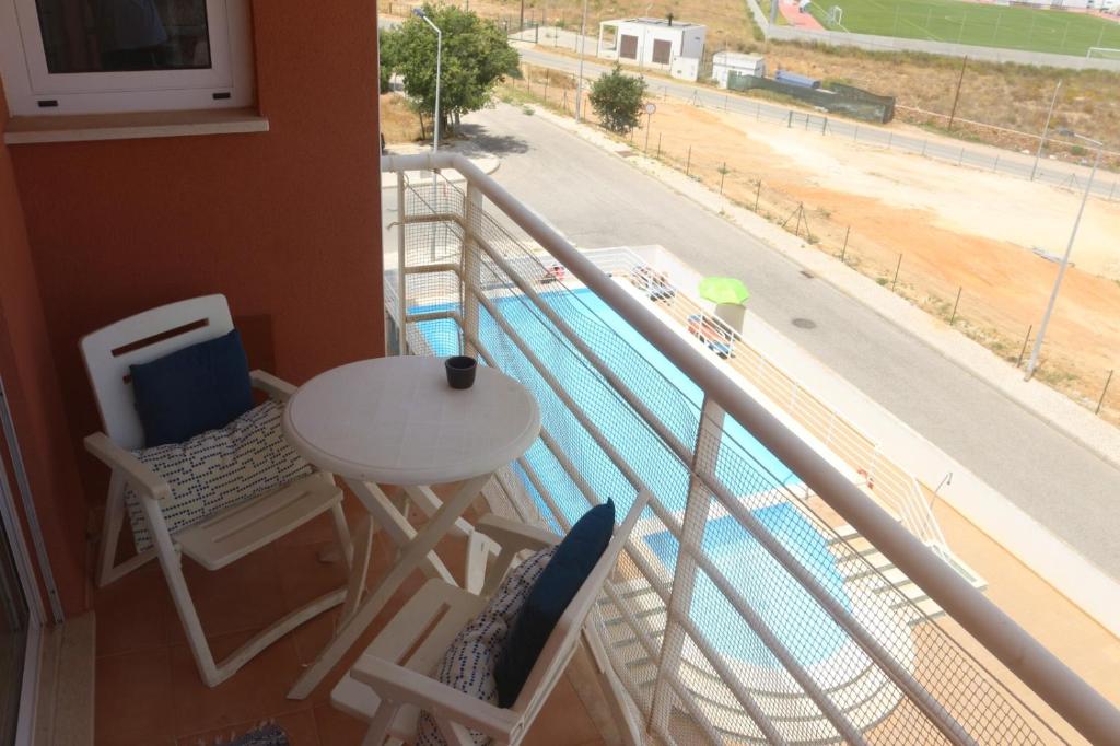 a balcony with a table and chairs and a view of a pool at Casa dos Avós - Quinas II in Armação de Pêra