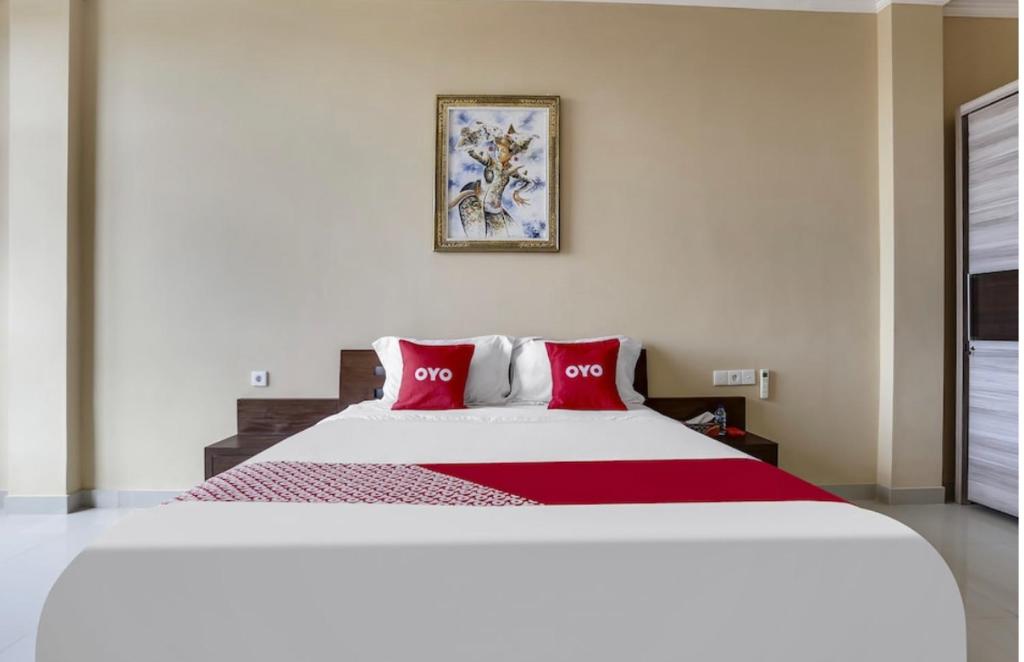 a bedroom with a large bed with red pillows at Moreno Homestay in Legian