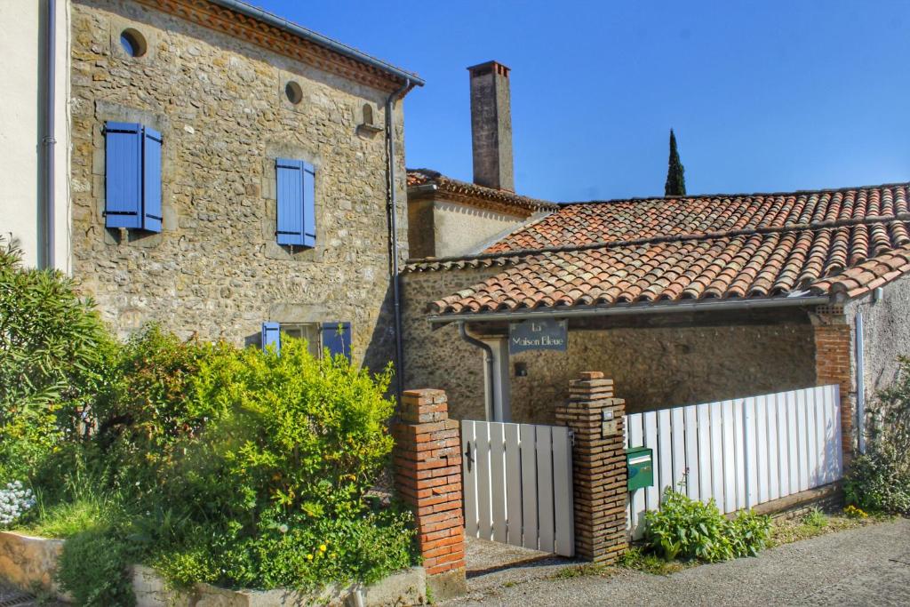 a brick house with a white fence in front of it at La maison bleue in Lautrec