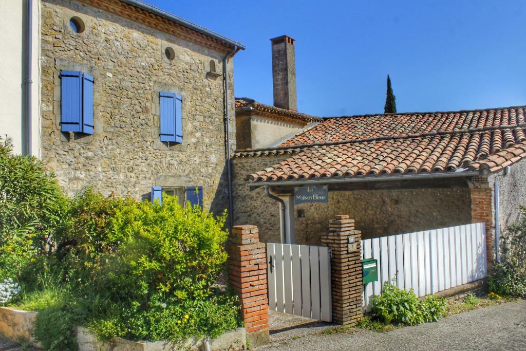 una casa di mattoni con una recinzione bianca di fronte di La maison bleue a Lautrec