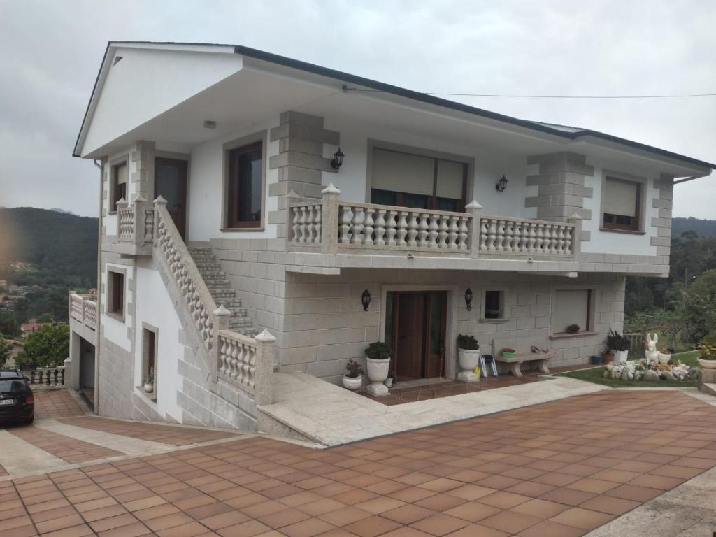 uma casa branca com uma varanda e uma entrada em Casa de vacaciones em Baiona