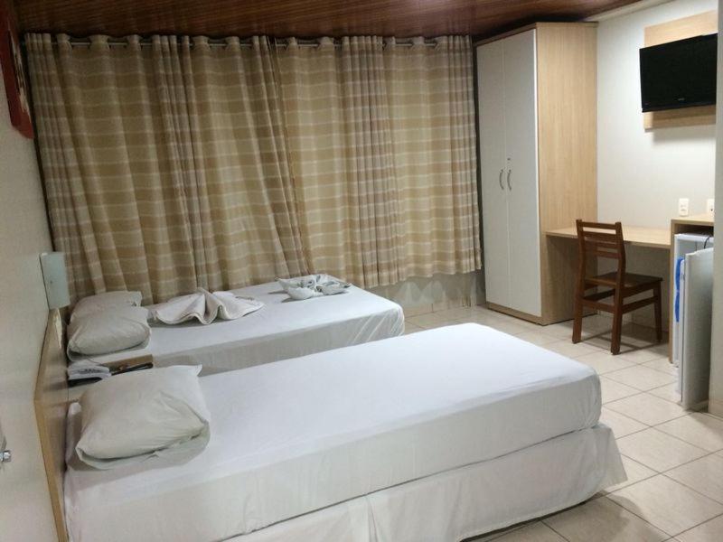 um quarto de hotel com duas camas e uma mesa em Swamy Hotel em Cruzeiro do Sul