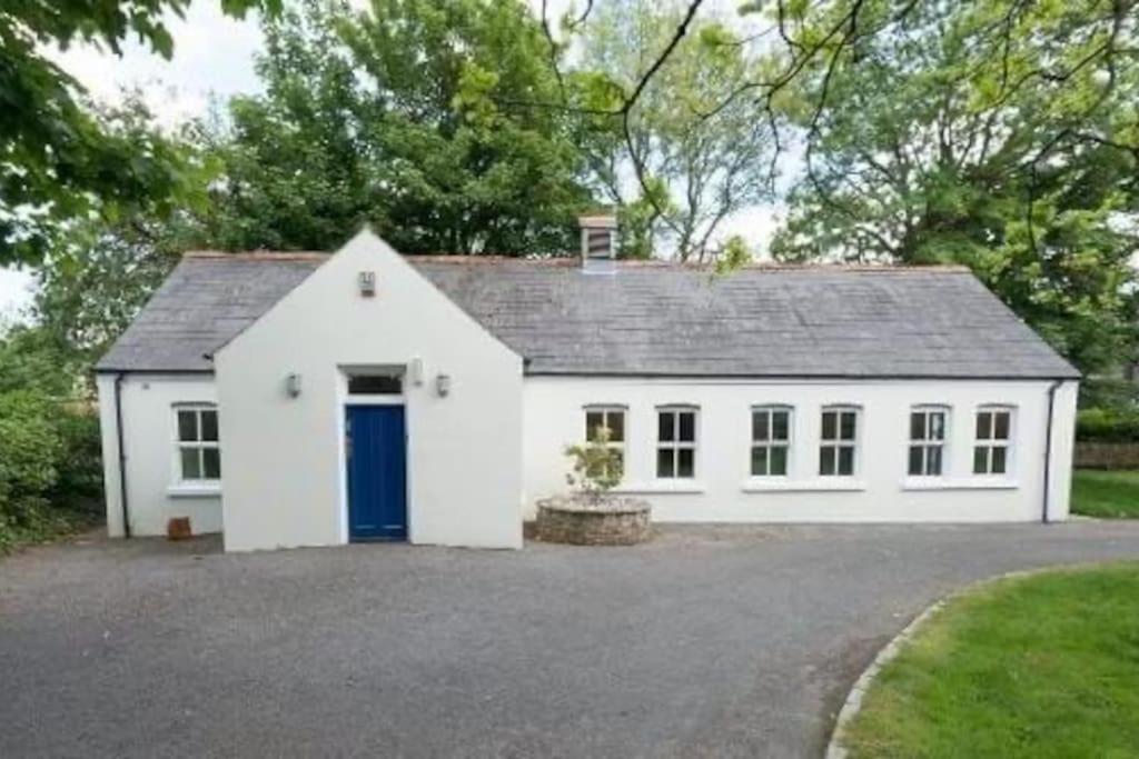 una casa blanca con una puerta azul en una entrada en Rose Cottage, en Irvinestown