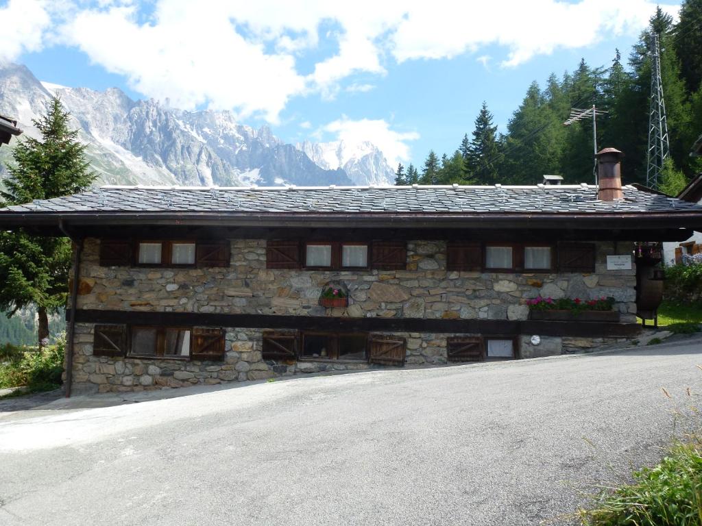 a stone building with mountains in the background at Il Refuge CIR 119 in Courmayeur