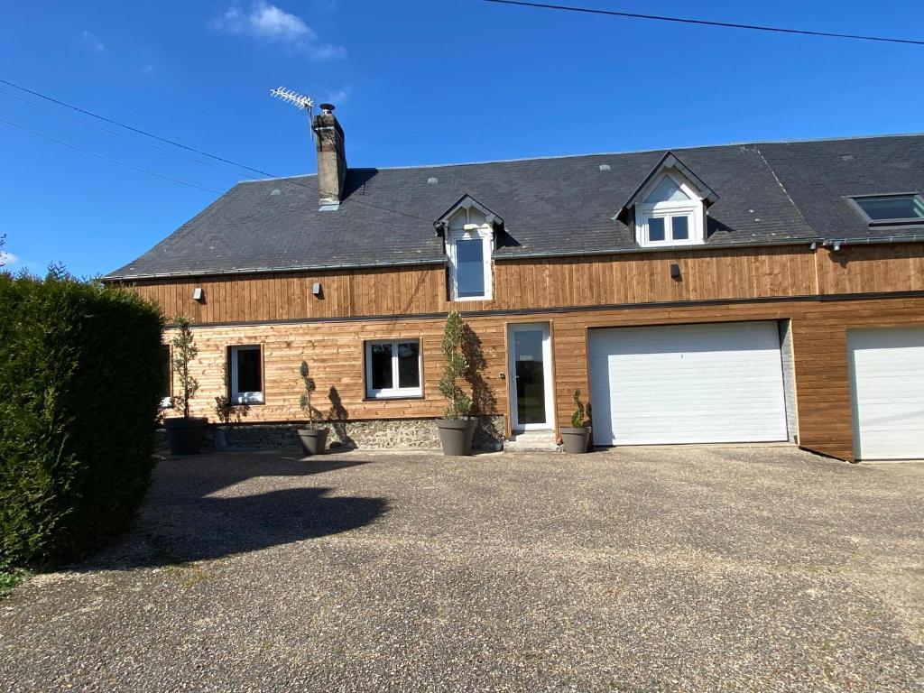 a large brick house with two garage doors at La Ferrière in Pissy-Pôville
