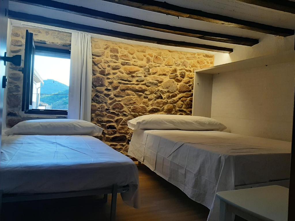 2 camas en una habitación con una pared de piedra en Casa rural rústica para parejas, familia o amigos a la montaña "EL COLMENAR", en Chóvar