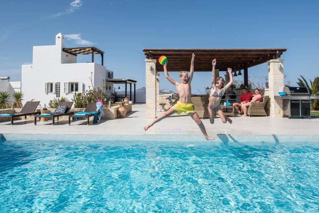 two people jumping into a swimming pool with a frisbee at Wonderful Villa Melodie in Plaka