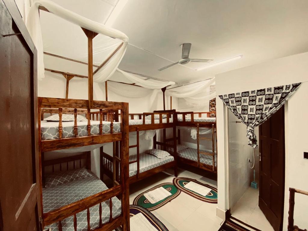 a room with three bunk beds in a house at Sanaa Hostel in Zanzibar City