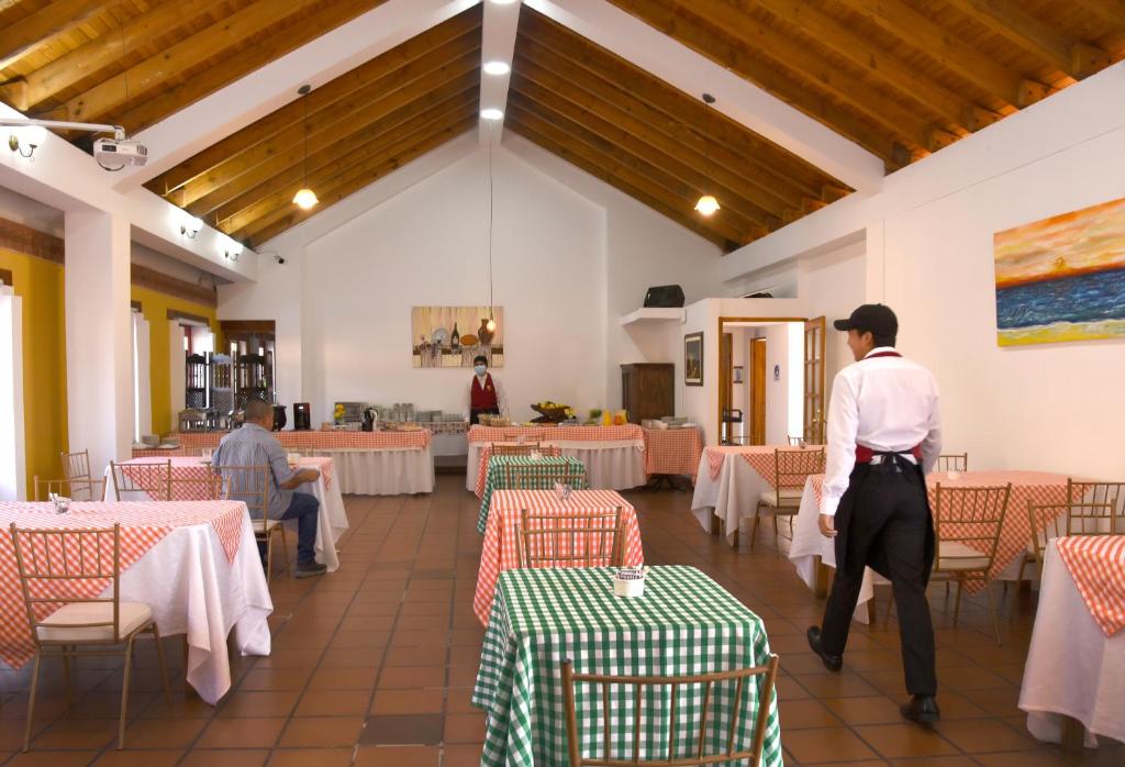a man standing in a dining room with tables at Hotel Cacique Real in Zipaquirá