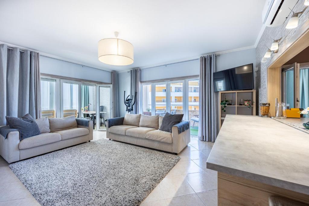 a living room with two couches and a rug at Convista Flat T2+1 in Portimão