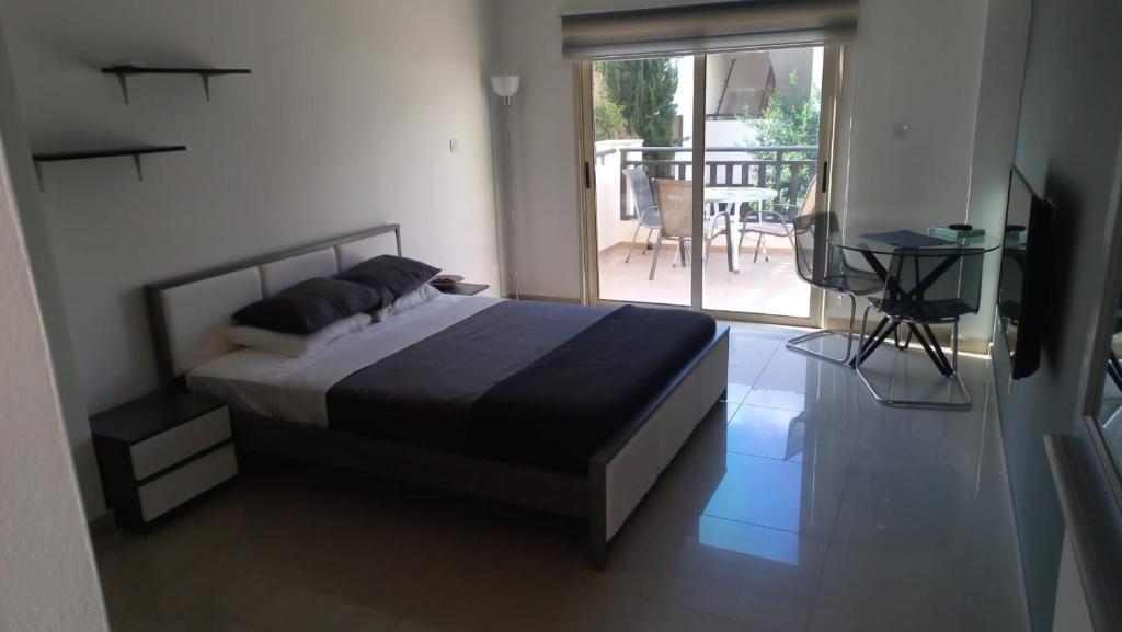 1 dormitorio con 1 cama y balcón con mesa en Modern Studio apartment Armonia Court, en Paralimni