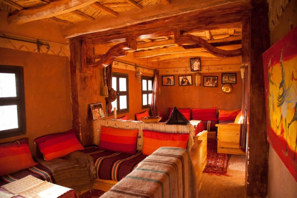 soggiorno con cuscini rossi e arancioni di Kasbah des montagnes maison d'hôtes a Bou Drarar