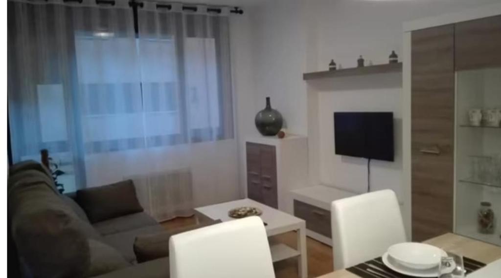 sala de estar con sofá y TV en La Escapada, en Posada de Llanes