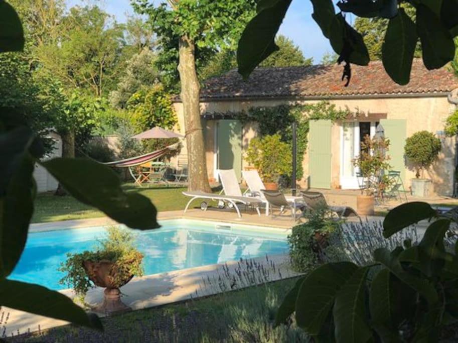 uma piscina com duas cadeiras e uma casa em Gîte 2-4 couchages situé dans un magnifique jardin em Saint-Vivien