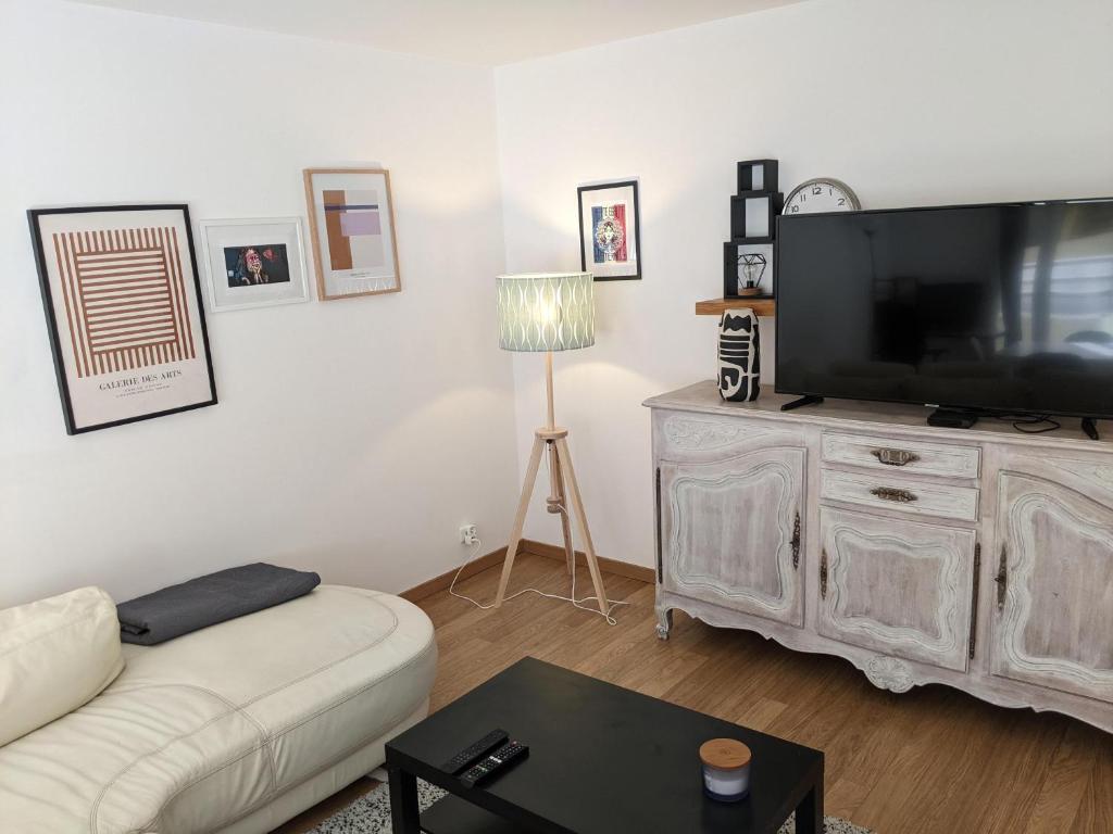 a living room with a white couch and a flat screen tv at Appartement SQY in Guyancourt