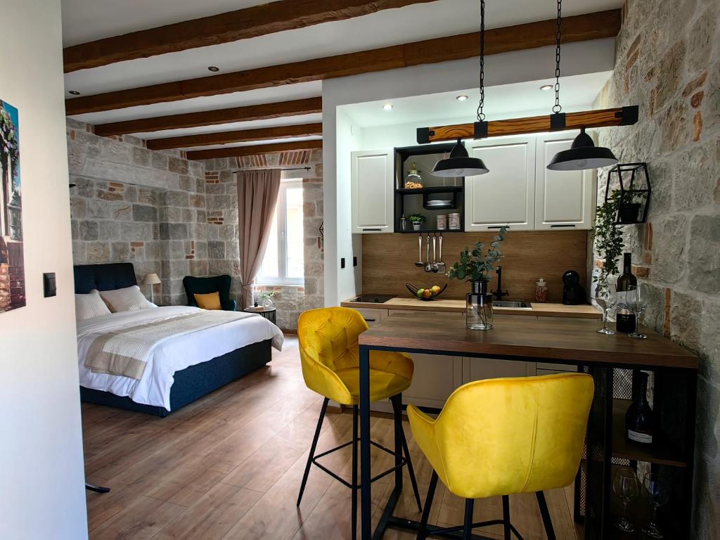 a bedroom with a bed and a kitchen with yellow chairs at Apartments Lana Spalato in Split