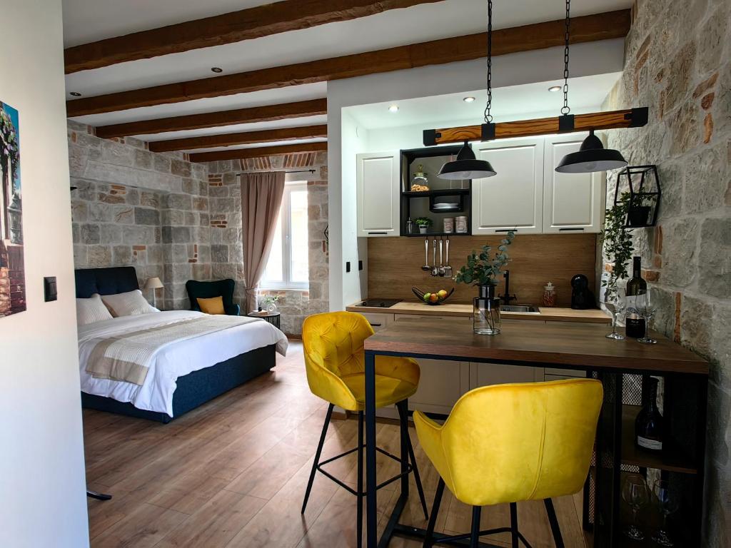 Cet appartement comprend une chambre avec un lit et une cuisine avec des chaises jaunes. dans l'établissement Apartments Lana Spalato, à Split