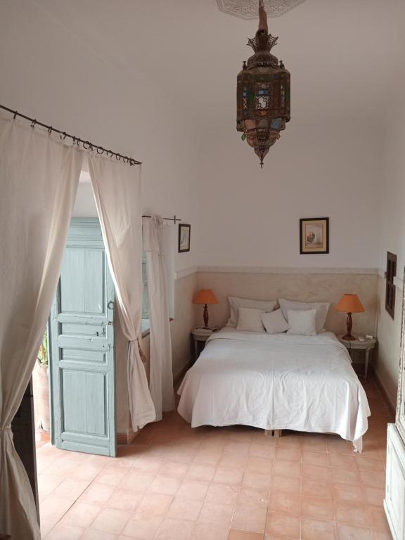 1 dormitorio con cama blanca y lámpara de araña en Riad le Jardin de Mina, en Marrakech
