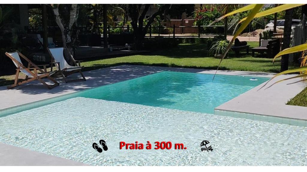 a swimming pool with blue water in a yard at Lá em Casa - Guest House in Barra Grande