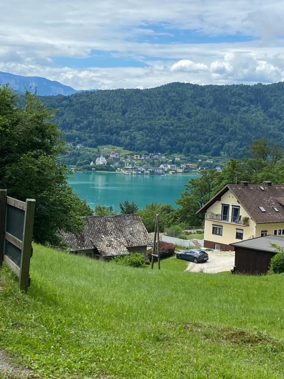 uma vista para um lago a partir de uma colina com uma casa em WALDHAUS HIRSCH Bungalow only for you self check in em Pörtschach am Wörthersee
