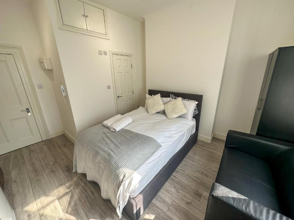 a small bedroom with a bed with white sheets and pillows at the upper floor in Croydon