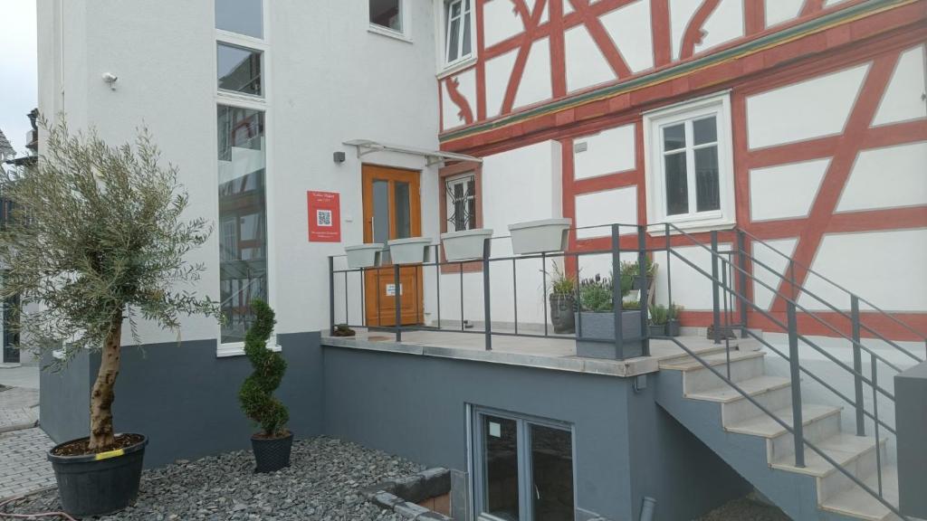 ein weißes Gebäude mit einer Treppe und einer Veranda in der Unterkunft Apartments & möblierte Zimmer in Kahl am Main, kontaktloser Self Check-in, W-Lan, Schreibtisch, Duschbad, Küchenzeile, PKW-Plätze in Kahl am Main