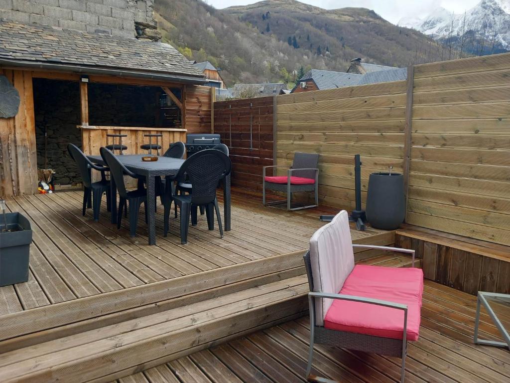 une terrasse en bois avec une table et des chaises dessus dans l'établissement Maison familiale 8 personnes au coeur de Loudenvielle, à Loudenvielle