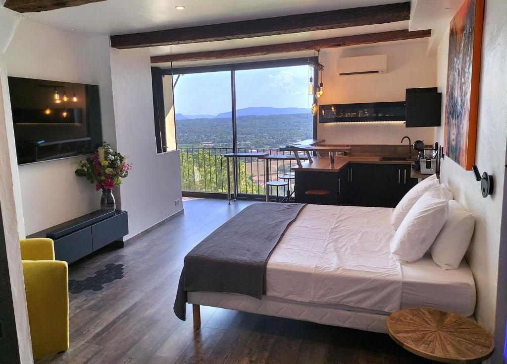 a bedroom with a bed and a desk and a balcony at L'essens in Fayence