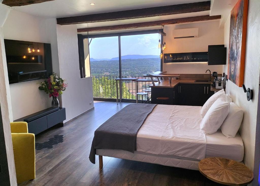 sypialnia z łóżkiem i biurkiem oraz balkon w obiekcie L'essens w mieście Fayence